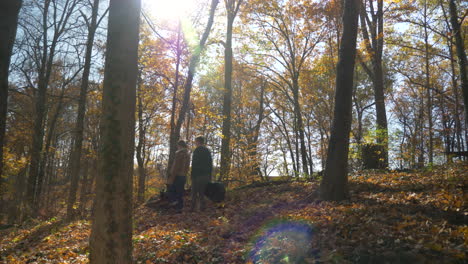 wide shot of two musicians walking in the woods in the fall