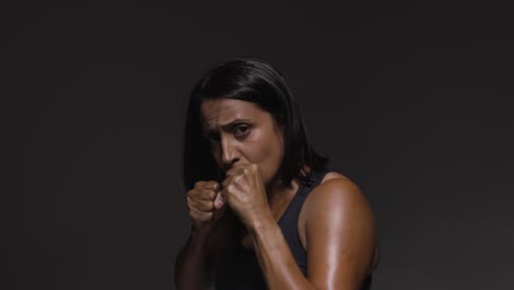 studio portrait of mature woman wearing gym fitness clothing exercising sparring at camera 2