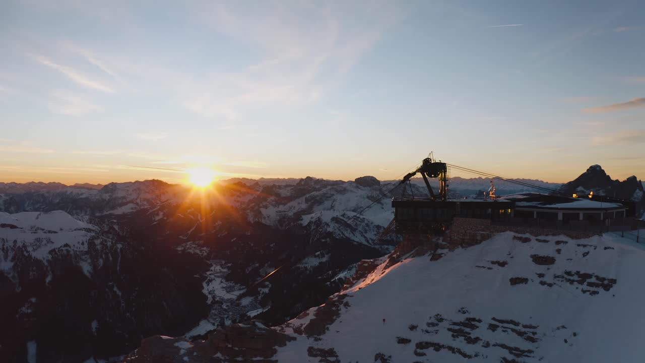 Gondola on Sass Pordoi at sunset with an orange sunburst