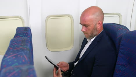 a revealing shot of a man on a plane using a tablet pc