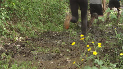 las piernas de los competidores corriendo por el barro en un curso de asalto