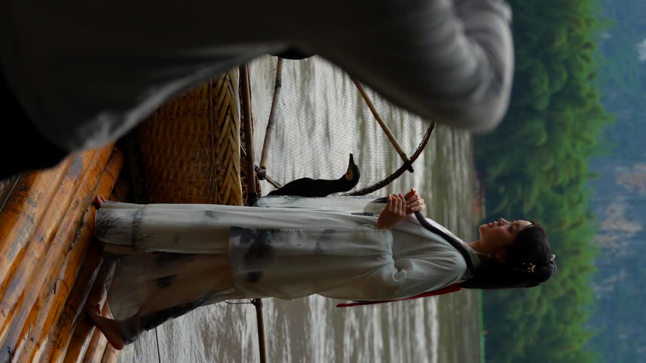 niña con ropa de hanfu posa para un fotógrafo en una balsa de bambú en xingping, china
