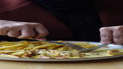 mujer comiendo pollo y papas fritas en un restaurante