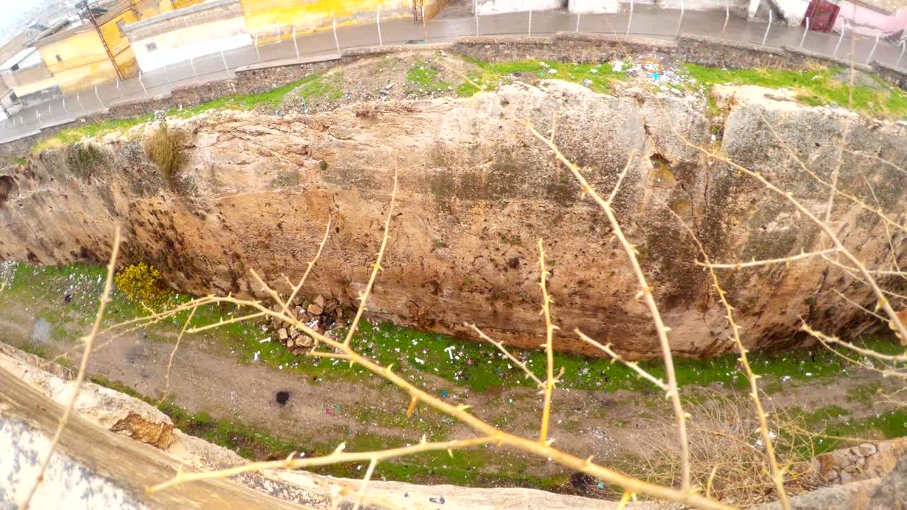 la zanja del castillo de urfa a través de ramas espinosas los pájaros vuelan en el hoyo la nieve y la lluvia
