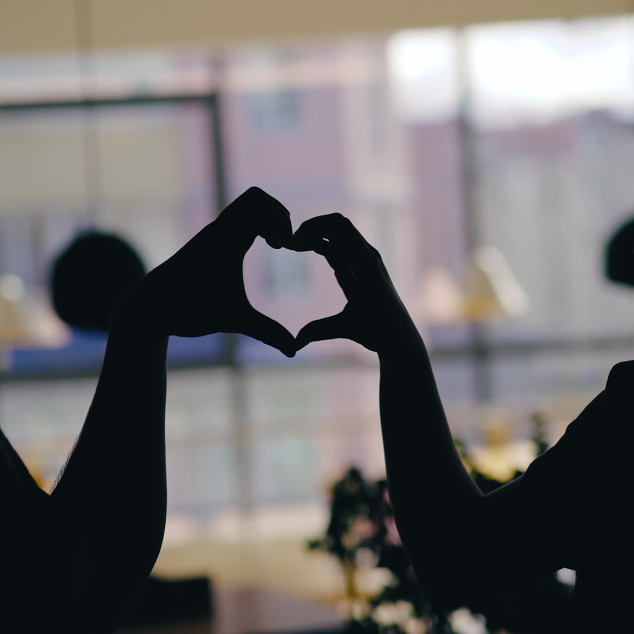 silhouettes of man and woman are talking at a table in the cafe and drinking drinks on the background of the window. Blurred background