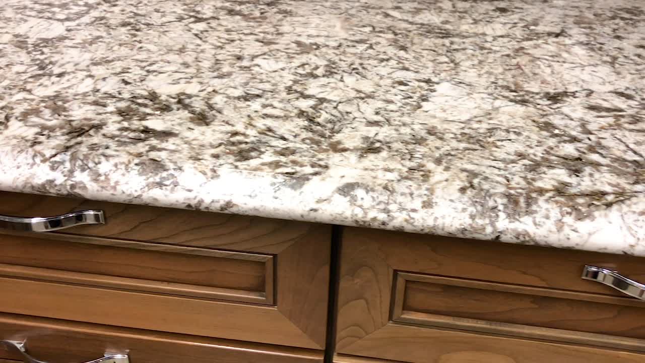 Meja dapur granit terbuat dari batu alam dalam warna abu-abu dan putih di atas lemari dapur kayu maple