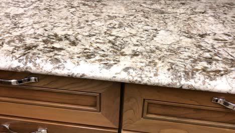 granite countertop made of natural stone in grown and white colors on maple kitchen wood cabinets