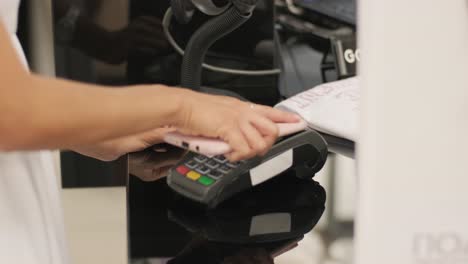 mobile payment concept - young woman pays by contactless phone to credit card system for her new clothes