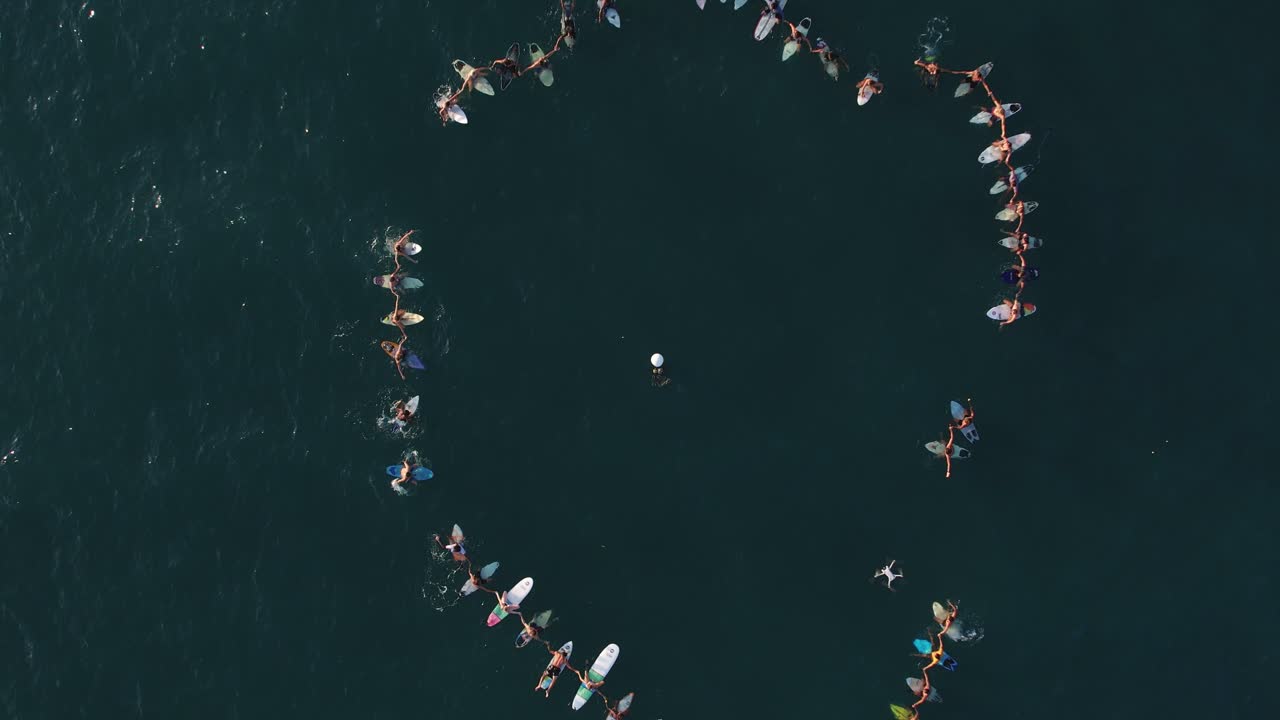 사마라 해변 에서 바다 에 떠다니는 수십 명 의 사람 들 이 서핑 보드 를 원형 으로 들고 있는 공중 상상