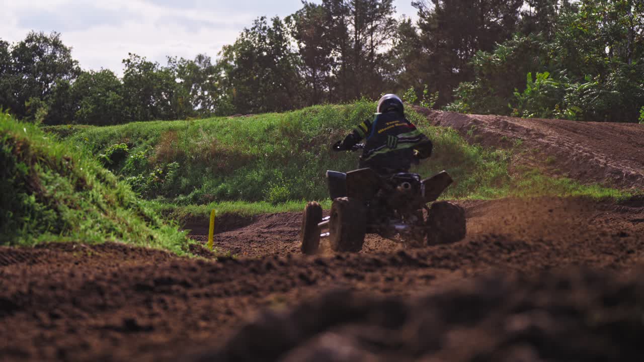 grupo de motociclistas en quad corriendo en un camino sucio y fangoso esparciendo arena debajo de las ruedas mientras ingresan a un giro con curvas en cámara lenta