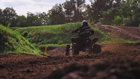 group of quad bikers racing on dirt muddy road scattering sand from under wheels while entering curvy turn in slow motion