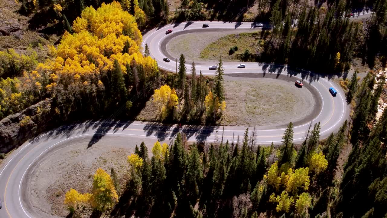 los coches que conducen la curva s de la autopista de un millón de dólares en colorado alineada con aspens dorados durante el otoño, aéreo