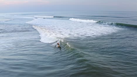 aerial: beautiful mexican surfing destination, surfer riding wave at sunset