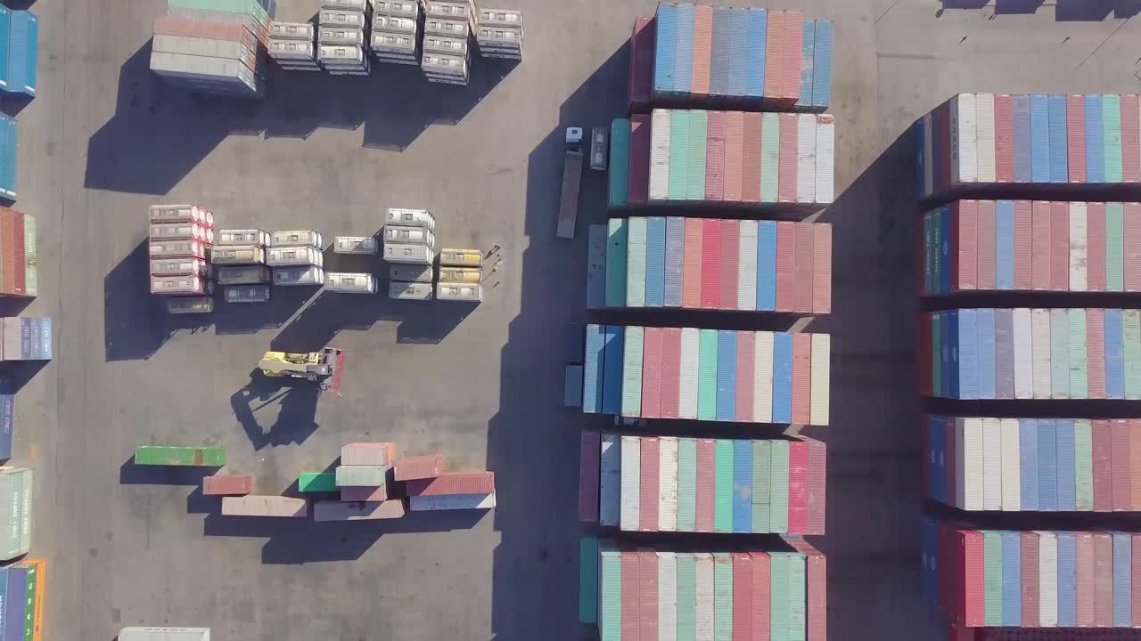 A cargo carrier moves a container through a container shipping yard and places it in another location