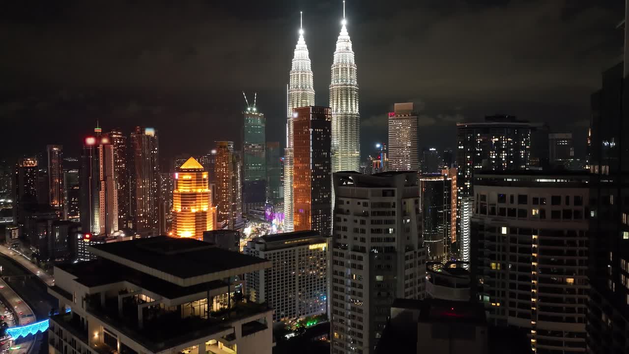 Toma aérea nocturna de establecimiento que revela las Torres Petronas en Kuala Lumpur, Malasia