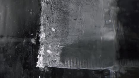 a bartender is cutting the ice block to smaller pieces for cocktail service by using a long toothed knife.