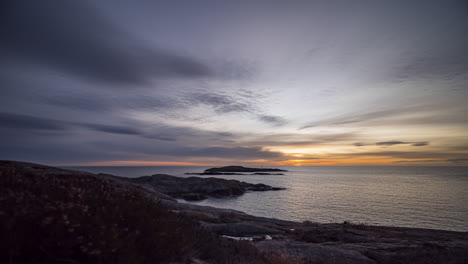 time lapse clouds move toward rising sun over ocean with rocky shore