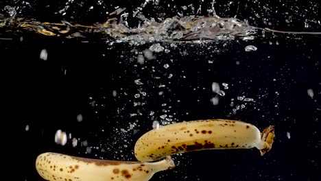 ripe bananas being dropped into water in slow motion