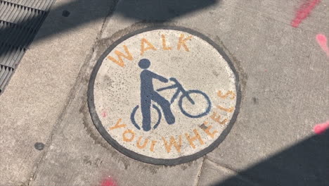 Sidewalk-bicycle-notice-to-walk-on-manhole-cover