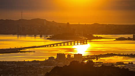 Puente-De-La-Bahía-De-San-Francisco-Y-Horizonte-De-La-Ciudad-Al-Atardecer---Lapso-De-Tiempo-De-Celaje-Dorado-Oakland-California