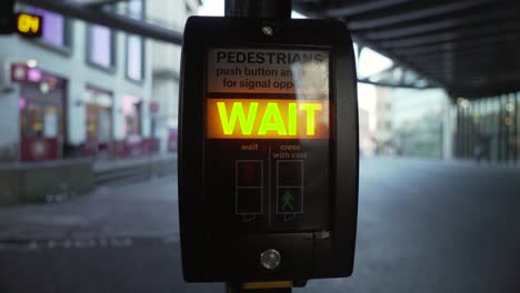 a close up shot of a pedestrian crossing machine being pressed by a black male with the wait sign illuminated