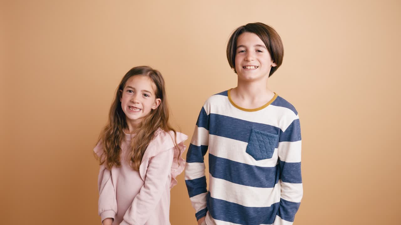 Ragazzo e ragazza felici che sorridono alla fotocamera in studio