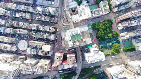 Traffic-passing-through-a-Car-park-building-in-downtown-Hong-Kong,-with-city-mega-buildings,-Aerial-view