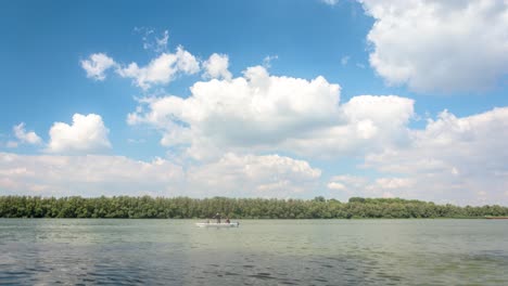 4k video time lapse of danube river with fishing boat and amazing clouds on the blue sky