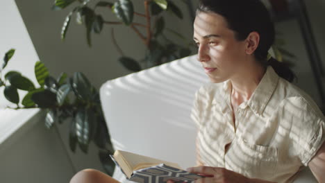 woman reading book and posing for camera at home