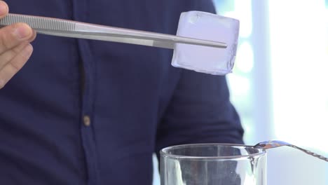 barman put ice in an alcohol drink in a glass