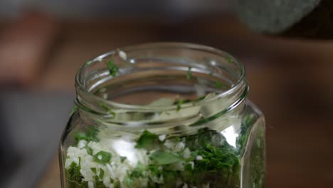 Geben-Sie-Salz-Aus-Einem-Mörser-Und-Stößel-Mit-Einem-Kleinen-Löffel-In-Das-Glas-Mit-Den-Zutaten,-Um-Das-Chimichurri-Zuzubereiten