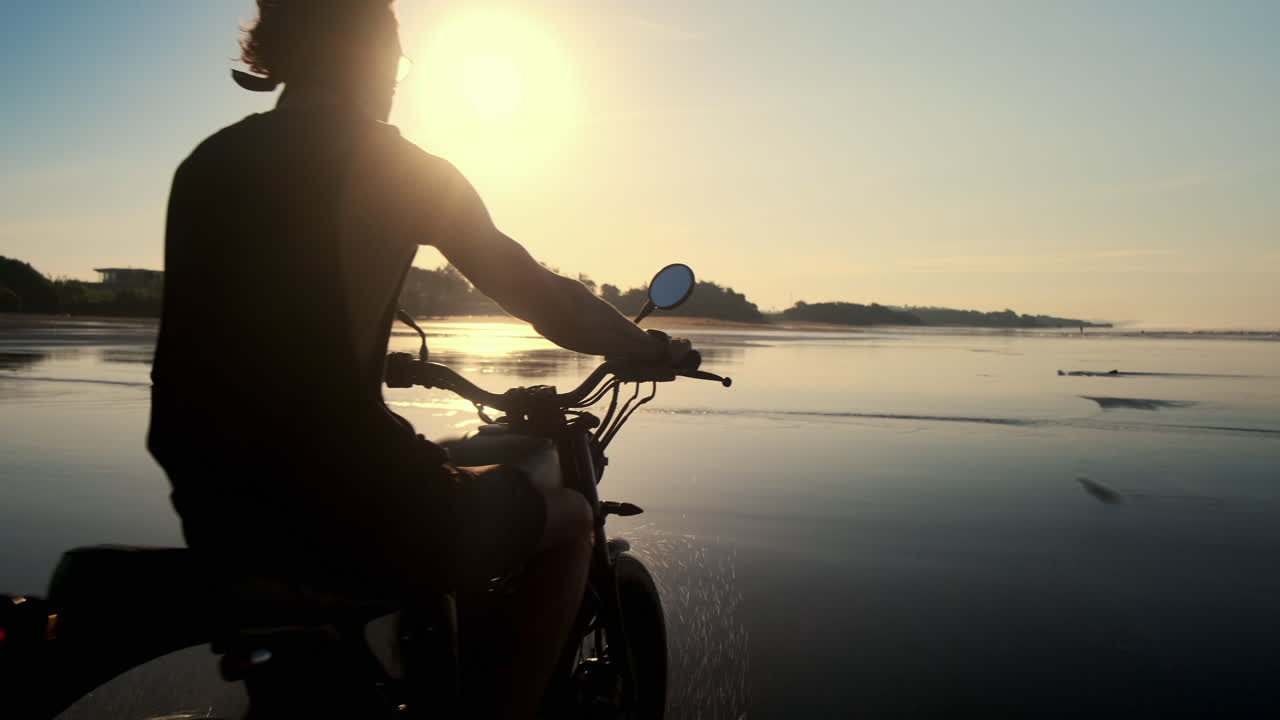 человек едет на мотоцикле на пляже на рассвете