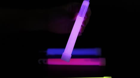 hand arranging colorful glow sticks in dark environment