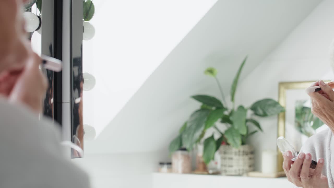 화장실에서 메이크업하는 고령 여성.