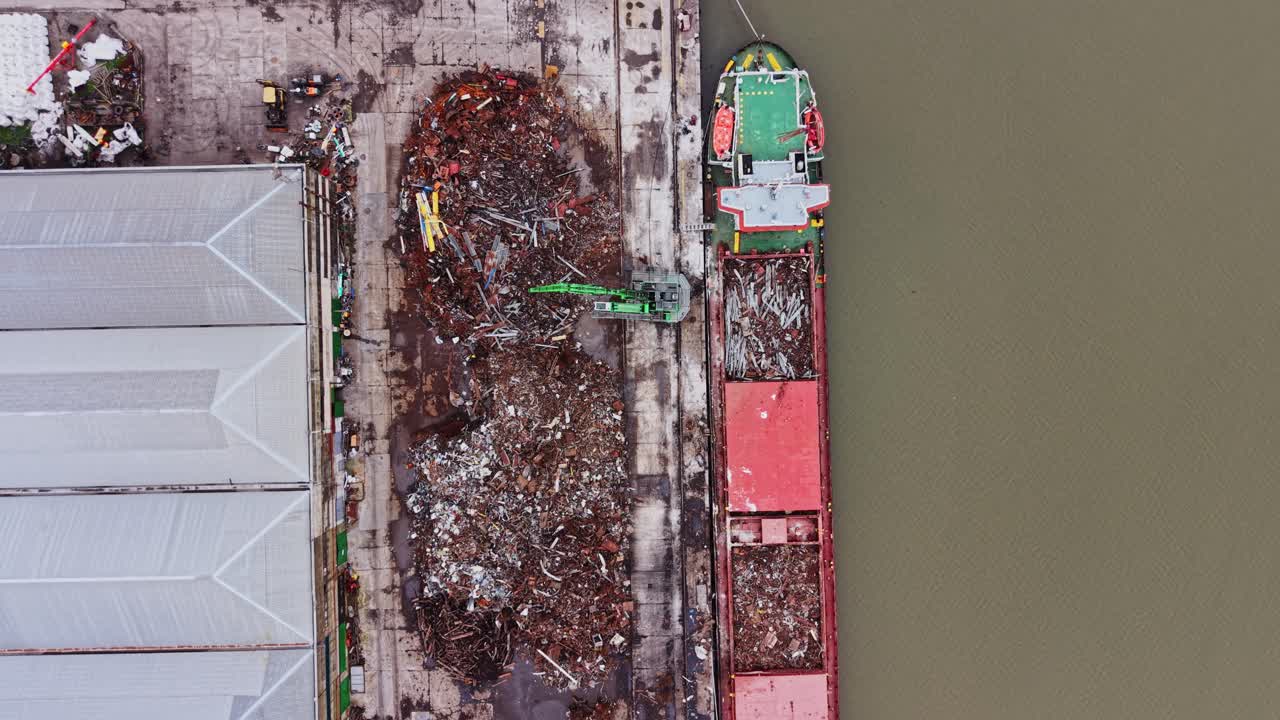 Nave da carico che viene caricata con rottami metallici in un cantiere navale in un porto trafficato.