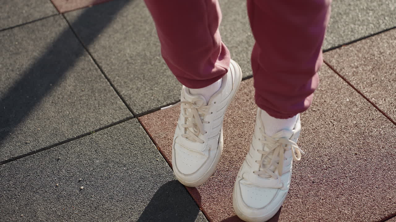 High angle view of gym lover jogging on spot with energetic movement on rubber playground surface under morning sunlight in urban park setting warming up for fitness routine and training session