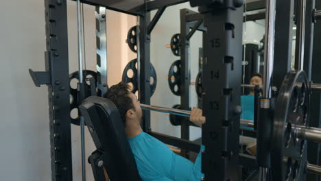 rutina de ejercicio de la parte superior del cuerpo, hombre de camisa azul haciendo press de hombro de barra sentado