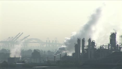 smoke rises from a petrochemical factory or oil refinery under a cloudy sky 1