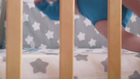 mamá toma a un niño pequeño en traje de vestir llorando en una cuna moderna