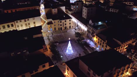 idyllic square with glowing christmas tree with star in madeira city at night, aerial