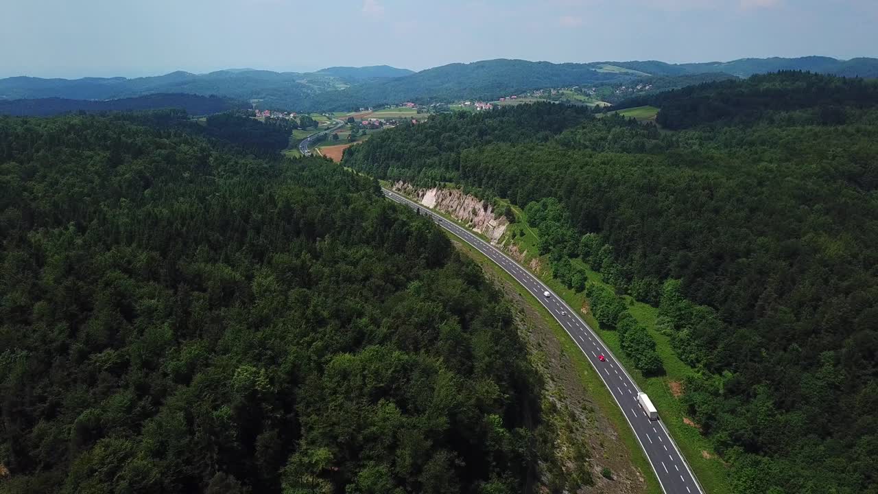 fotografía aérea de una carretera de montaña rodeada por un bosque verde