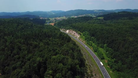 Aerial-shot-of-a-mountain-road-surrounded-by-a-green-forest