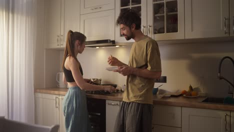 pareja cocinando y comiendo juntos en la cocina
