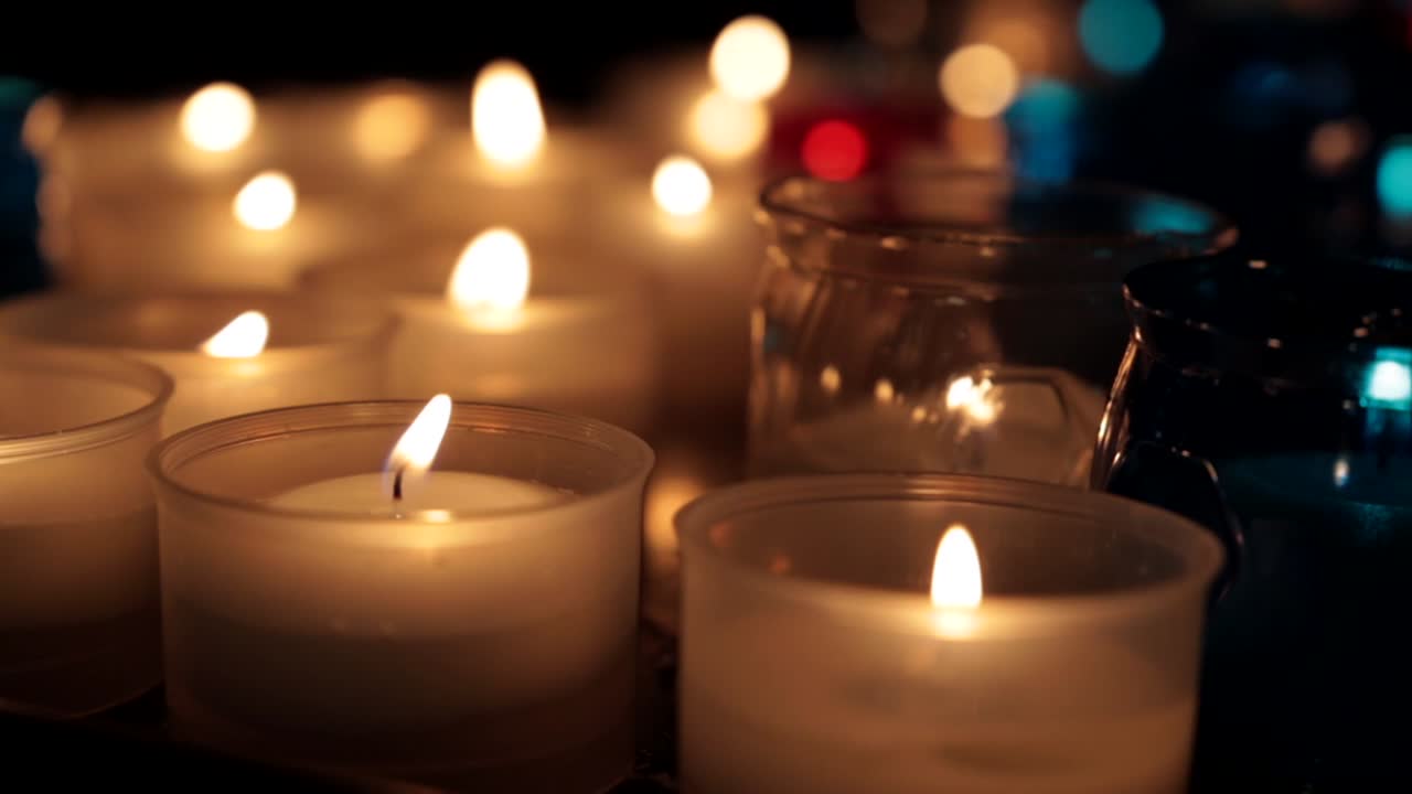 Macro shot of a tray of candles in different colors inside a church