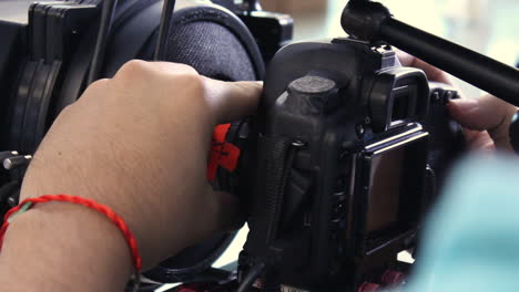 hand of a man pulling the focus on a lens of a cinema professional camera