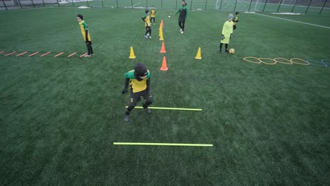 a children's football team trains at the stadium under the guidance of a coach. kids in sports uniforms practice ball exercises, improve technique, and develop teamwork on the green field