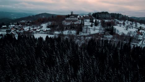 vista de pájaro del bosque de invierno oscuro y el resort de montaña al atardecer nublado