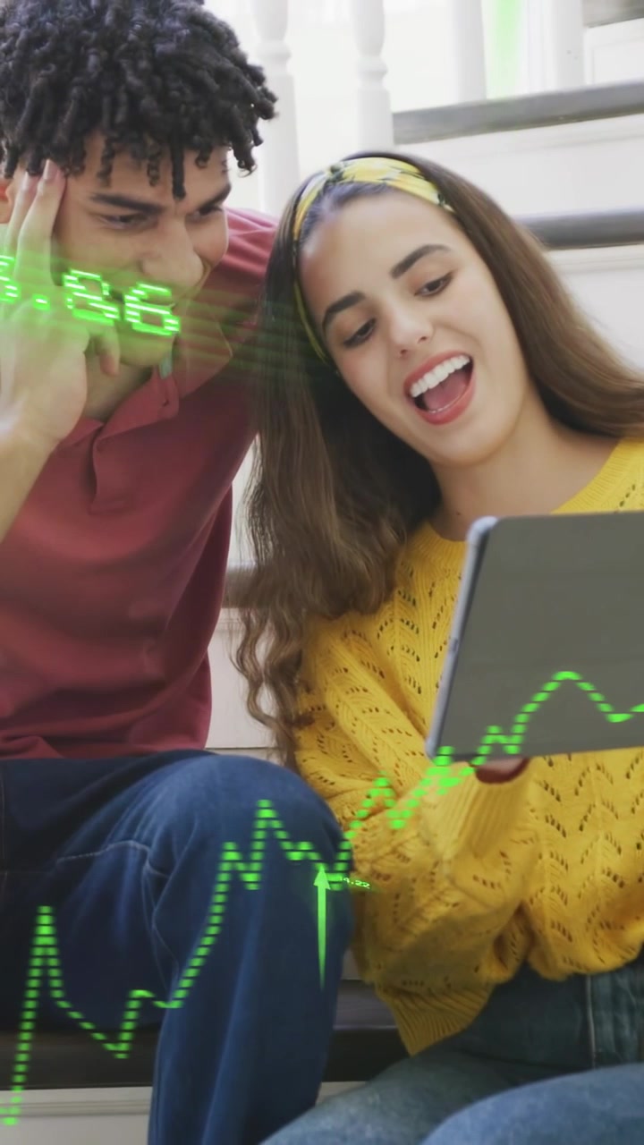 Video vertical: Dúo en las escaleras inclinando una tablet, viendo un gráfico financiero verde subir y siguiendo las ganancias.