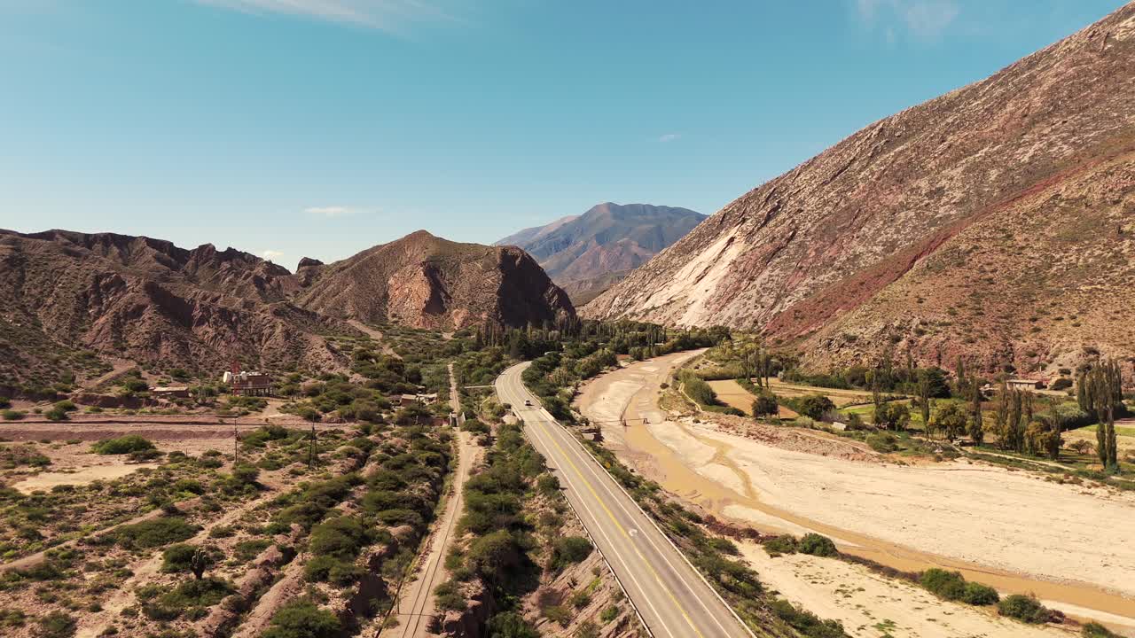 Scenic aerial view of a winding road and dry riverbed through a mountainous valley