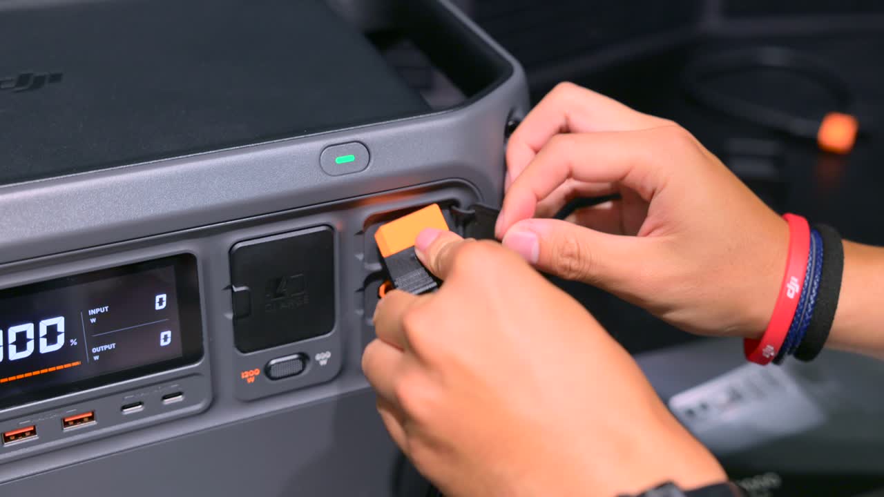 Close-up of a person plugging in leads to a large battery pack, showcasing technology and innovation at the IFA Berlin trade show.